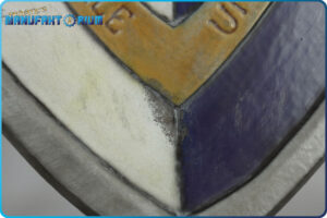 Detailansicht vom LARP Schild Löwe und Greif. Abgeplatzte Farbe, unter der metallische Farbe sich zeigt.