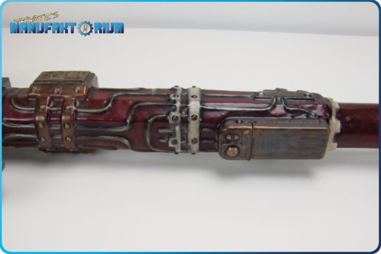Detailansicht des roten Schafts der LARP Waffe Energieaxt Mk. 1. Batterifach in Kupferfarbe. silberne und weiße Verzierungen.