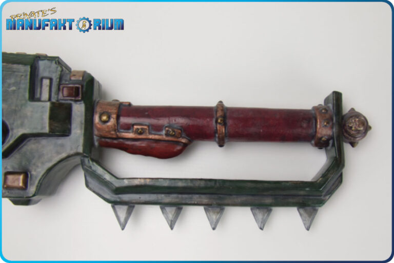 Detailansicht der LARP Waffe Kettenschwert MK.1 Griffbereich mit versteckten Schalter. Am Handschutz des roten 2-Hand Griffs dreieckige Spikes.