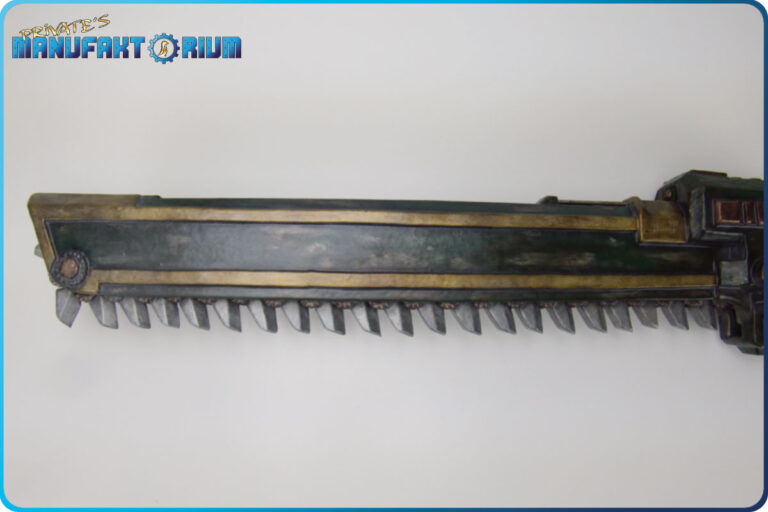 Detailansicht der LARP Waffe Kettenschwert MK.1 Klingenbereich mit den Zähnen. Gehäuse in Grün mit abgeplatzter Farbe und goldenen Verzierungen.